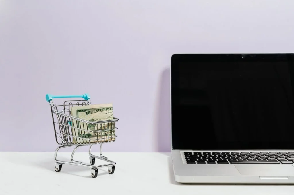 How To Earn Google AdSense Income Income macbook pro on white table beside a miniature shopping cart with money