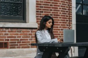 attentive ethnic female entrepreneur typing on laptop in town