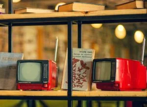 book on shelf between toy retro tvs